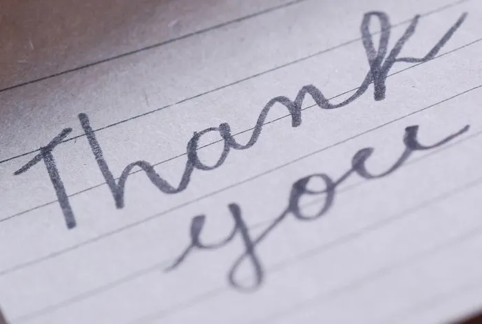 Original photo of the words Thank you handwritten in cursive on lined paper