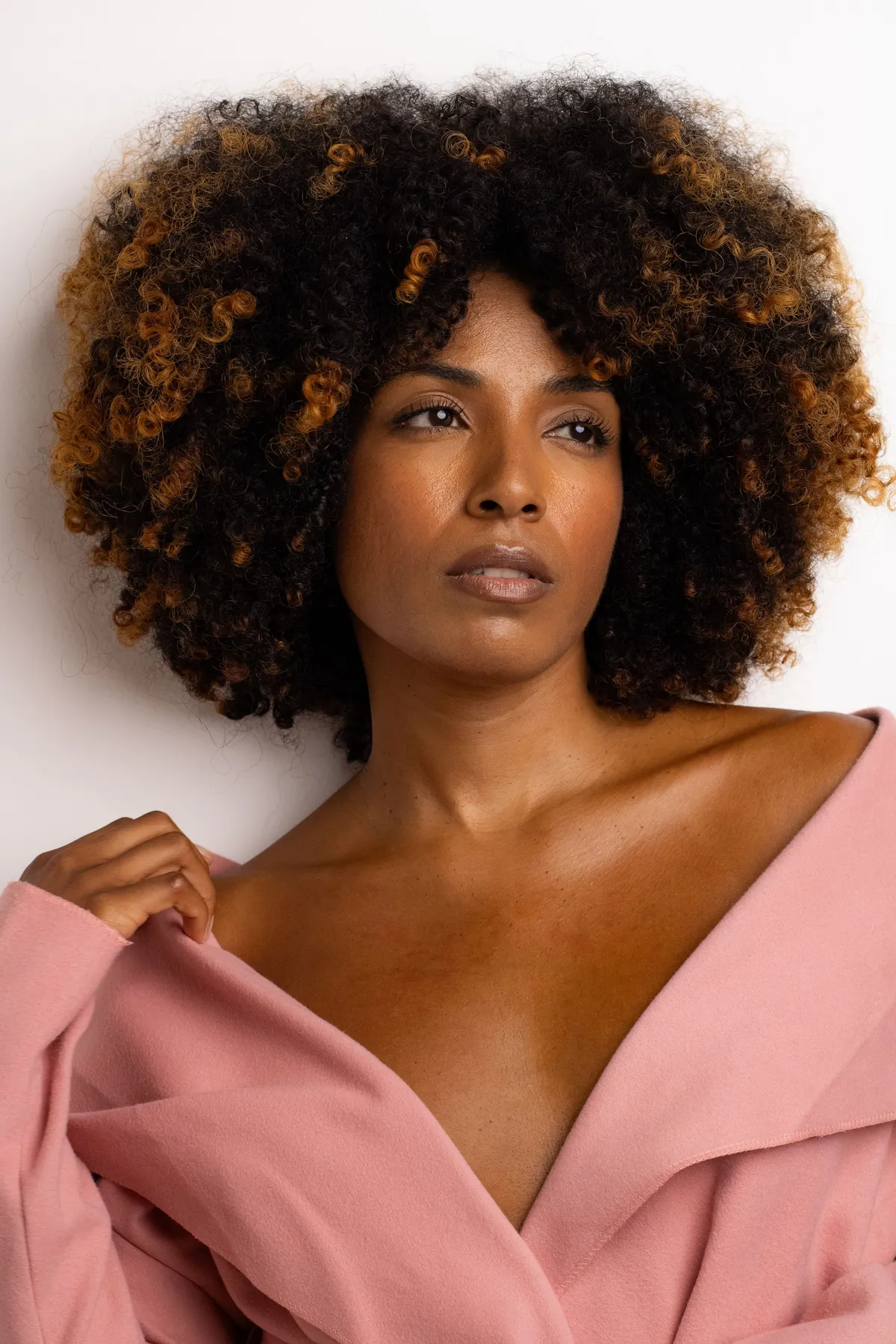 Original studio portrait of a woman with voluminous curly hair in a pink blazer