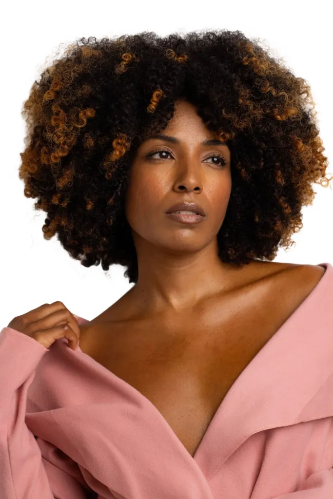 Curly-haired portrait in a pink blazer on a clean white background after AI background removal