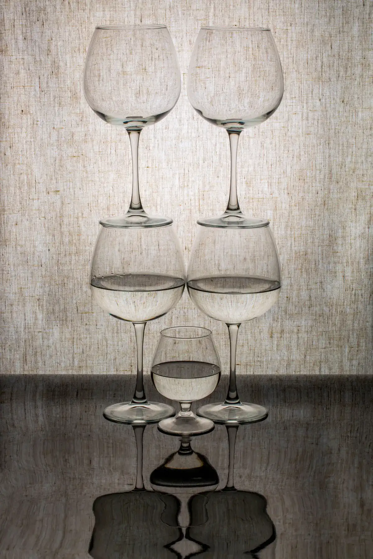 Original still life photo of five stacked wine glasses against a gray textured backdrop